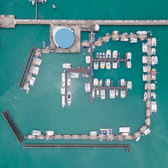 Aerial drone view of Chalong Pier in Phuket, Thailand. Many boats, yachts and speed boats moored at the pier platform of Ao Chalong Bay, one of centers to travel around Andaman Sea.