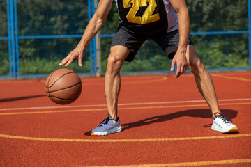 Unrecognizable man playing basketball at court.