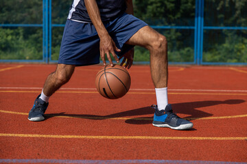 Naklejka premium Unrecognizable man playing basketball at court.