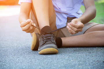 Closeup image of tying shoelace getting ready for exercise afterschool of asian schoolboy, concept of preventing the risk of falls of all people around the world. - obrazy, fototapety, plakaty