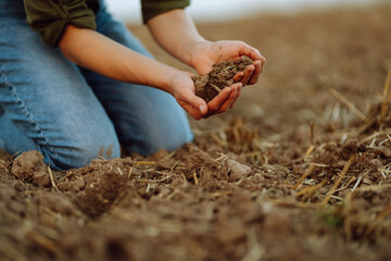 Close-up of a woman farmer's hands holding fresh soil. An experienced farmer checks the quality of...