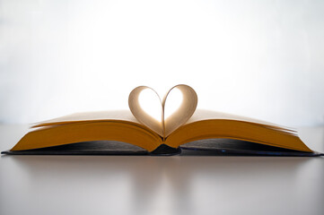 Open book and pages folded to form a heart, on a white background. Passion for reading.
