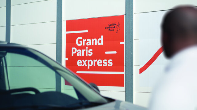 October 2023, A Sign Of Grand Paris Express Futur Subway In A Suburb Of Paris, Val-de-Marne. Blurry Passer-by On The Foreground.