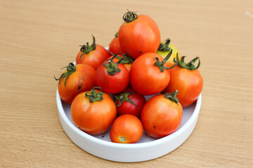 tomat or fresh tomato on white plate on a wooden background