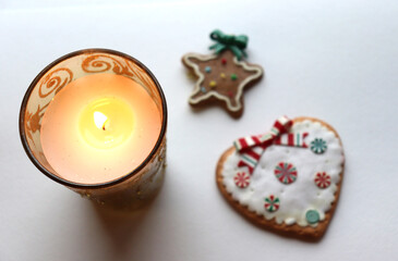 photo Burning candle in a glass candlestick and Christmas cookies on the table, top view