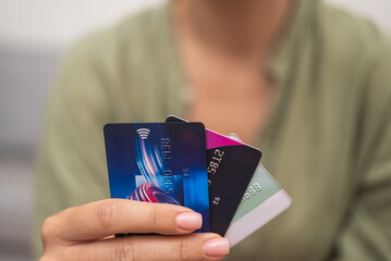 Close-up: Woman's hand grasps a stack of credit cards, symbolizing online payments, shopping, and the use of contactless cards. 