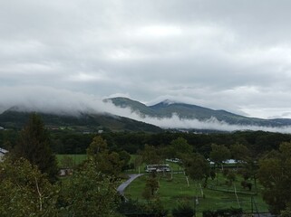 Mountains in clouds at sunrise in summer. Aerial view of mountain peak with green trees in sugadaira nagano japan.