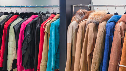 Multicolor women's coats, fur coats and jackets on hangers in the store