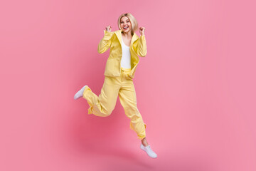 Full length portrait of carefree delighted person jump raise fists empty space isolated on pink color background