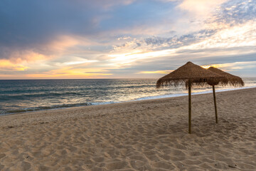 Sunset on sandy beach with ocean waves and colorful sky and clouds, Algarve, Portugal