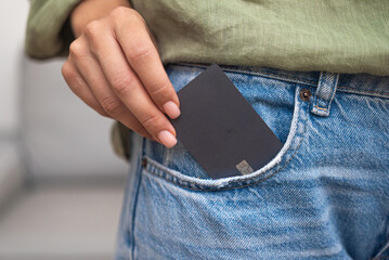 Streamlined shopping: A lady's hand pulls a dark credit card with a chip from her jeans pocket,...