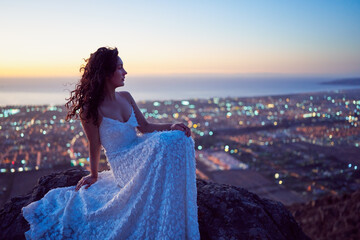artistic portrait beauty beautiful hispanic woman sitting on the top of a hill with white dress over the city at sunset