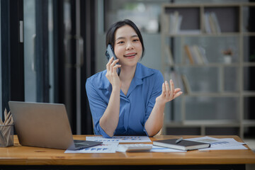 Asian businesswoman using smartphone sitting at desk in office, working online, 