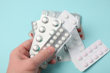 A male hand holds a package of pills. Pills blister in the hand.