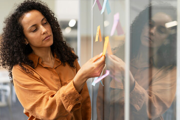Businesswoman using sticky notes, agile methodology for productivity working in modern office
