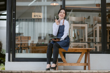 Fototapeta premium Happy smelling Asian woman owner with open sign broad and ready to service, Small startup business concept.