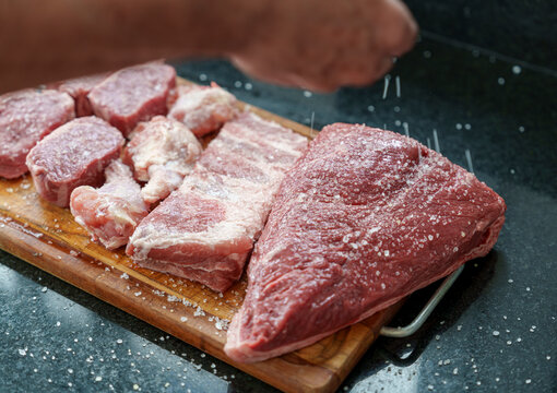 Temperando as carnes para churrasco com sal grosso. Colocando sal grosso com a m&atilde;o sobre os cortes para churrasco de picanha, costela, frango, ancho.