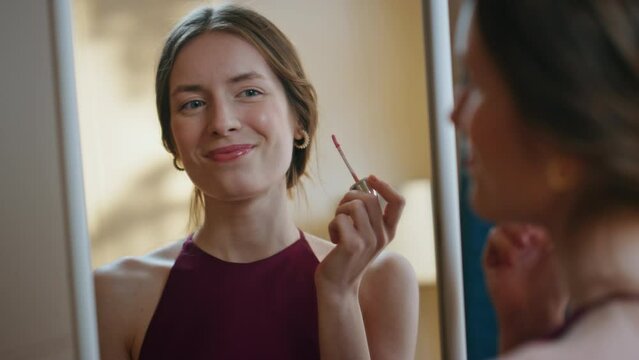 Gorgeous girl applying lipstick in mirror reflection closeup. Joyful model enjoy