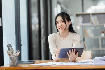 Fototapeta na wymiar Woman worker feeling excited and euphoric winning, Young woman excited sitting at desk office, Overjoyed woman, Attractive woman triumph sit at desk wit digital tablet win online.