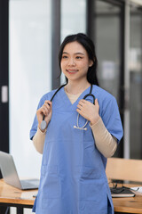 Healthcare and medical staff concept. Young Asian female doctor with a stethoscope standing in medical practice. 