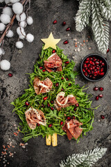 Jamon Prosciutto and arugula Salad, Christmas food tree Antipasto. Festive holiday food. vertical image. top view. place for text