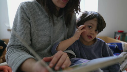 Mother Reading Book to Little Boy Sitting at Bedside, Child Absorbed by Story, Engaged Parenting in Motherhood Lifestyle Scene