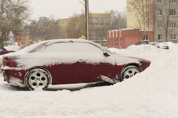 A snow-covered car stands in a snowdrift.