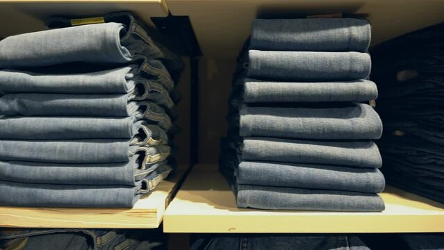 Stacks of blue denim pants are neatly laid out on a shelf in the store