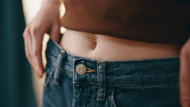 Hands fastening jeans button closeup. Woman checking waist weight loss progress