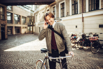 Middle aged businessman talking on his smartphone while going to work on bike in the city