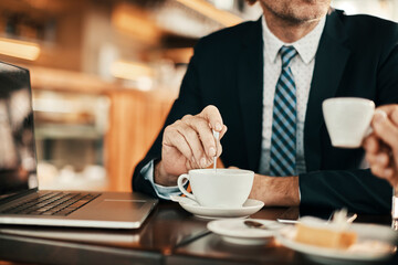 Close up of a businessman stirring his coffee on a meeting with a colleague in a cafe