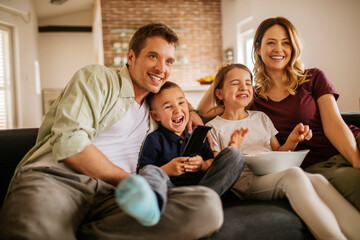 Happy young family watching a movie on the couch at home