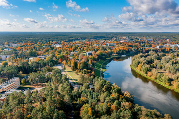 Autumn colours in the city, drone picture of small town covered in multi coloured leafs and river flowing beside