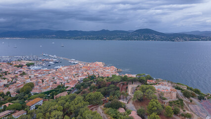 Fototapeta na wymiar Aerial view of Saint-Tropez and the marina. Photography was shot from a drone at a higher altitude with the bay in the background, on a cloudy day. Photo was taken from a drone from above the city.