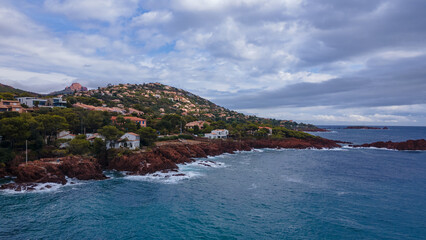 Fototapeta premium Aerial video of the Agay bay on the French Riviera. In the photography can be seen Agay lighthouse and a panorama of the bay, with mountains in the background. Photography was shot on a cloudy day.