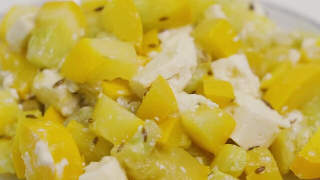 A plate with a prepared dish of zucchini and feta cheese is spinning on the table. View from above. Close-up, presentation.