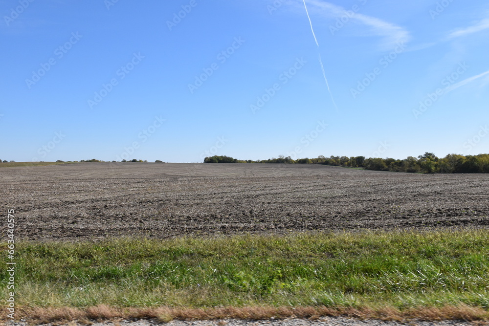 Sticker contrail and clouds over a farm field