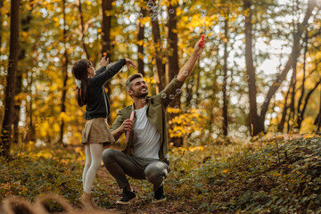 Father and daughter blowing bubbles in the woods