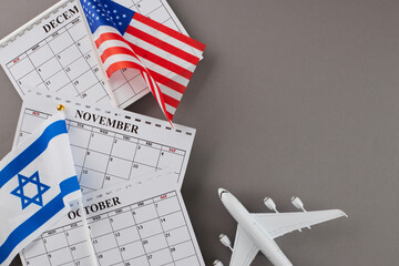 Problems with U.S.-Israel flight connections. Top view shot of calendars, American flag and Israeli flag, airplane on grey background with empty space for special text