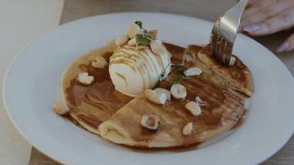Pancakes on a plate, with ice cream, nuts and sweet and sour sauce. Close-up
