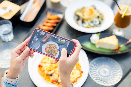 Woman cellphone to take photo on the food in restaurant