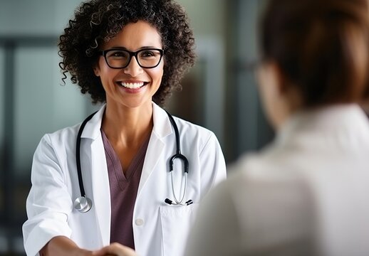 Portrait of smiling african american female doctor talking to female patient in hospital office. Medicine and healthcare concept