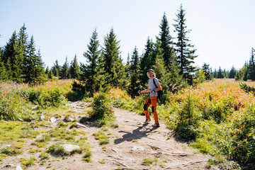 Man tourist in the mountains walking along the trail to the top, guy with backpack on his back walking along the road up, traveling alone, curly haired man.