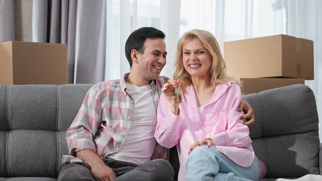 Happy family move into new house. Fun couple sit sofa. Joy people buy apartment. Guy sale cozy couch. Real estate mortgage concept. Adult girl rent flat. Home relocation. Man show key. Love portrait.