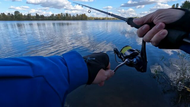 POV, Fisherman standing at the seashore hooks a fish. Sportsman holds a fishing rod and reel in a hooked fish.Point of view, Spin Fishing hobby catching a fish 