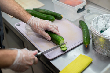 The chef cuts a cucumber with a sushi or salad knife.
