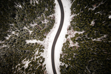 Snowy forest with road serpentine in winter mountains. Top down view. Landscape photography