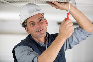 builder drives screws into ceiling