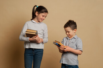 Boy and girl reading a book in studio. Studying and education.