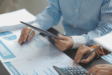 Financial analysts analyze business financial reports on a digital tablet planning investment project during a discussion at a meeting of corporate showing the results of their successful teamwork.